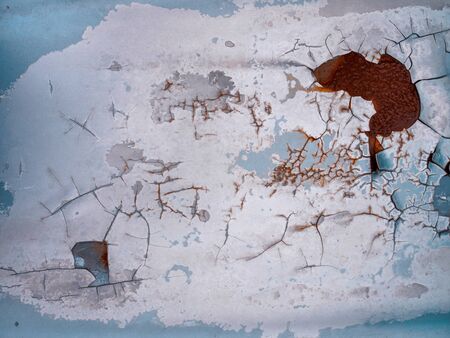 Worn rusty metal surface with paint flaking and cracking texture background.の写真素材