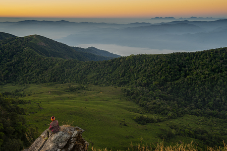 Man in red looking at the sunrise from the top of the mountain, Monjong, Chiang Mai, Thailandの写真素材