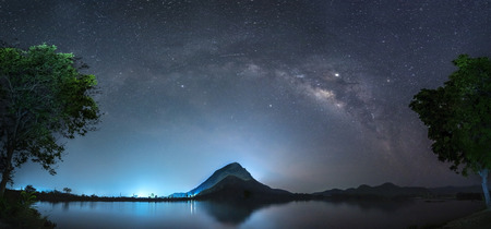 Night sky with stars and The Milky Way is above the mountain and reflection on the water (Lam Isu Reservoir) Kanchanaburi, Thailandの写真素材