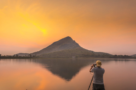 Photographer stands to take pictures of mountains reflecting water before sunrise.の写真素材