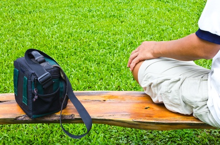 Sit with handbag on a wooden bridge over the piece of grass.の写真素材