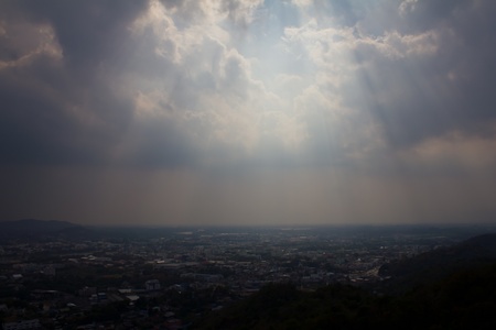 Fog over the city where the sun shines down from the clouds.の写真素材