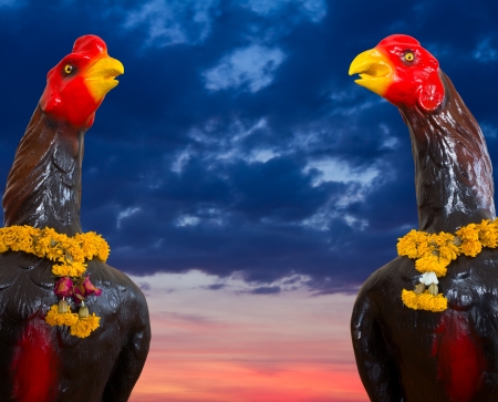 Cloudy scenes, two black statue of a chicken with a garland of flowers wilting in the neck の写真素材