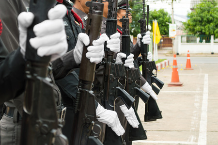 A row of police wearing white gloves holding a gun to salute.
