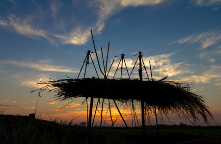 Silhouette Tripod three thatched roof on the grass under the sun rise.の写真素材