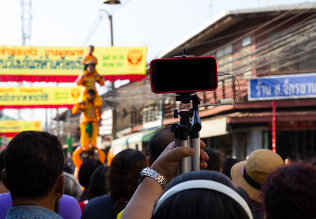 Photographers holds a tripod with a telephone installed to capture the scene.の写真素材