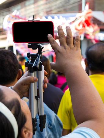 Photographers holds a tripod with a telephone installed to capture the scene.の写真素材