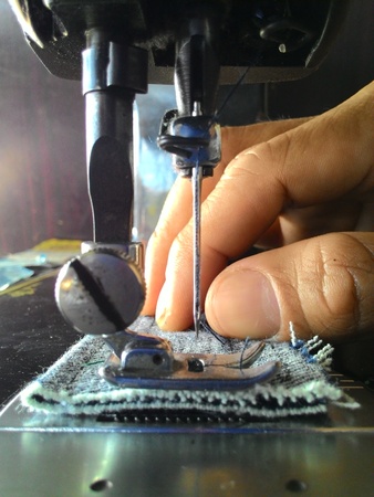 Close-up of old sewing needle with fingers Male to scrap denim.