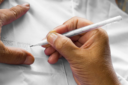 Close up of pencilwritten letters the name of Thailand on a white cloth skilled.