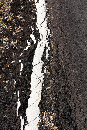 Background texture cracked asphalt road close to the long white line on the road side.の写真素材