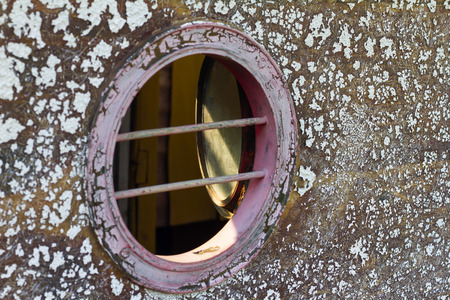 Close round peephole of old vintage wooden boat, which weathered and peeling paint.の写真素材