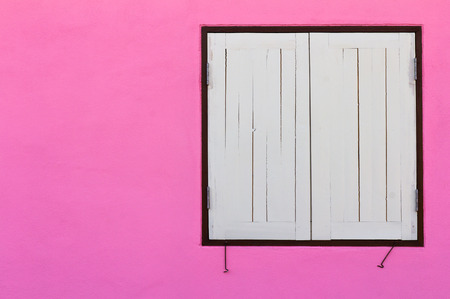 Old wooden windows closed on a white concrete wall in a house beautifully pink.の写真素材