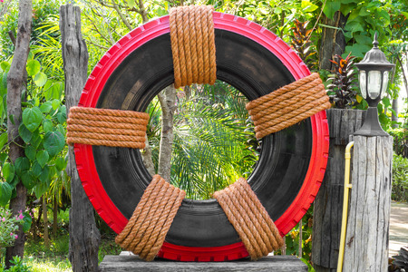 Tires Wheels black with a red tie with a brown manila rope is decorated in a beautiful garden.の写真素材
