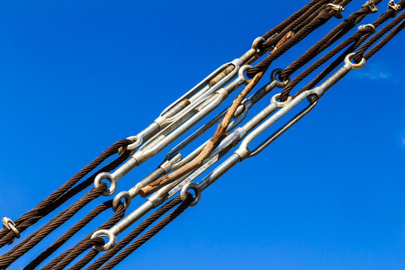 Close up of wire rope stretched taut with strong joints with wood stuck through the sky.