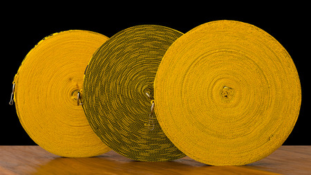 Isolate roll rope three large yellow patterned which is placed on a wooden floor.
