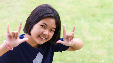 Young girls face beaming and holding a finger as a symbol of cheerful on the lawn.の写真素材