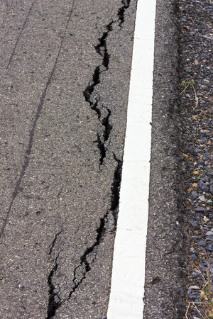 Close background which paved surface cracks near the white line, which caused the collapse of the basement.の写真素材