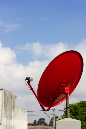 Red satellite dish, which is usually mounted on buildings common with the sky as a backdrop.の写真素材