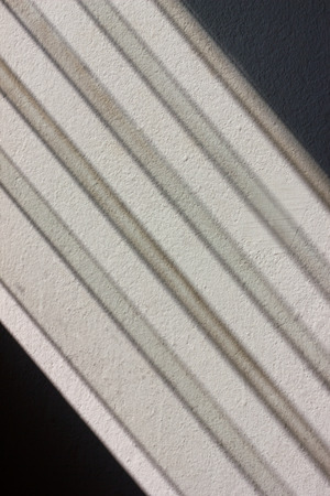 Long rectangular shape of the reflection of sunlight from the window shutters hits a concrete wall.の写真素材