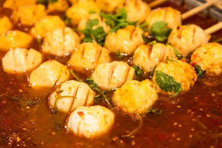 Close meatball skewers of chicken, white lined drowned in a delicious spicy sauce.の写真素材