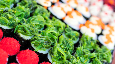 Many colorful candy sushi on a black tray to fully discharge its delicious typical flea market.の写真素材