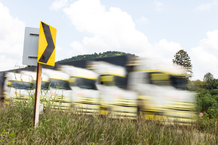Close-up truck which motion blur while sailing near a signpost on the road to the mountain.の写真素材