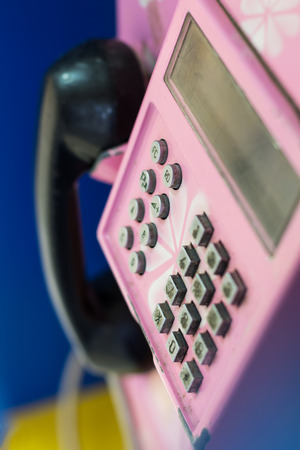 Close above blurred keypad buttons inside the old pink phone with a black handle.の写真素材