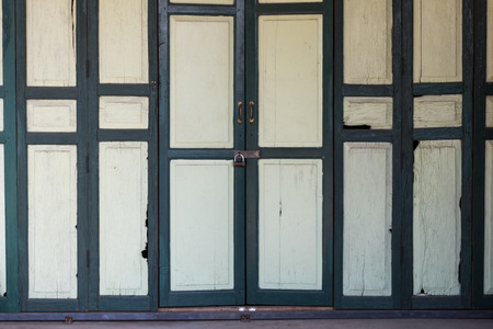 Background wooden doors and small green houses traditional key lock installed on a house.の写真素材