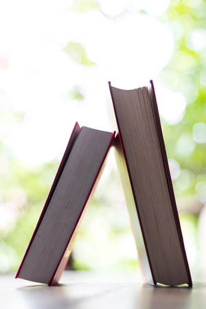 Close-up shots of two hardcover books lying on a table with a bokeh background blurred.の写真素材