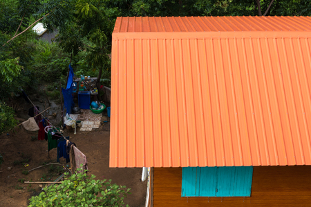 Close-up view from above New orange roof zinc on a rustic rural ground covered with trees.