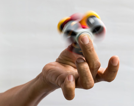 Isolate Thai finger man holding a spinning red spinner with a spinning yellow color which is a popular toy.の写真素材