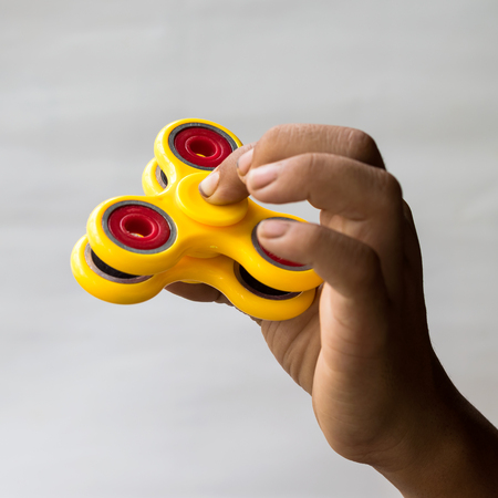 Thai boy finger trap is holding a red and yellow spinner, both of which are popular toys.の写真素材