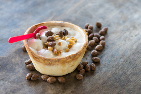 Close-up view of white icecream in soft coconut balls, with nuts and candies sprinkled on wooden floor.の写真素材