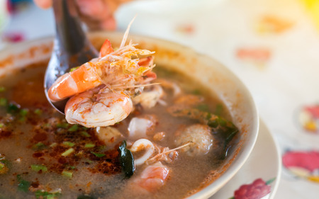 Close up of two shrimp in a spoon over a delicious Tom Yum soup is a popular food in the Thai countryside.の写真素材