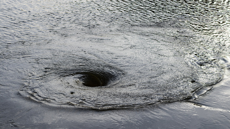 Background Surface Tides flow into a circular spiral into a large tube that is flooded.