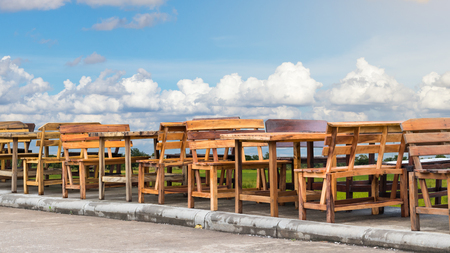 Many wooden benches and benches are laid out in rows on the concrete side of the road, which has a sky background.の写真素材