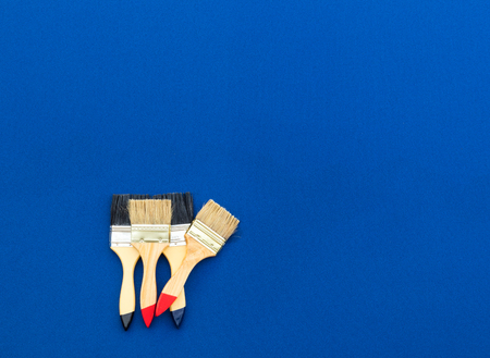 Four painted brushes were cleaned and placed on a blue cloth with empty space.の写真素材