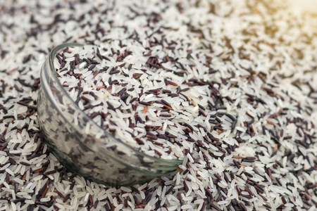 Close-up background heap of rice grains in both black and white mixed glass which is prepared lap.の写真素材