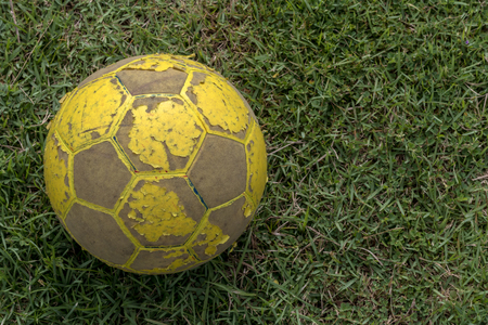 Close-up of old yellow soccer ball, which has long been kicked on the grass calmly.の写真素材