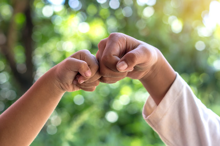 Close-up fist bumps between the two boys to Thailand friendship with bokeh green light blur in the...