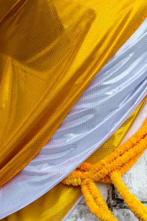 Background image, close-up surface, yellow patterned fabric overlapping with white cover, buddha and hanging garland.の写真素材