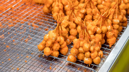 Close-up of many crispy dough balls, which are plugged with wood, are placed on the grill for sale...