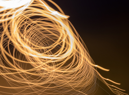 Abstract background, light lines of yellow lanterns on a circular street, swirling, scattering in the dark.の写真素材