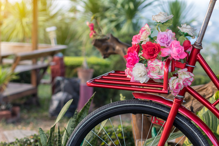 Close-up of colorful artificial flower bouquet placed on a vintage antique bicycle in a Thai garden.の写真素材