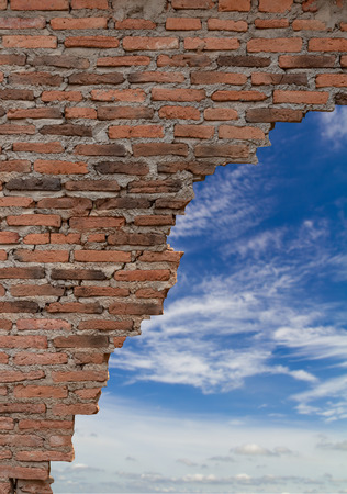 Close-up background, the ruins of an old brick wall which is broken and weathered for a long time with the sky clouds as the scene.の写真素材