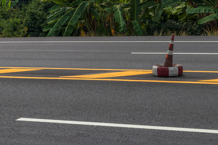 Close-up view of the side of the paved road, which has a yellow line symbol near the rural agricultural area.の写真素材
