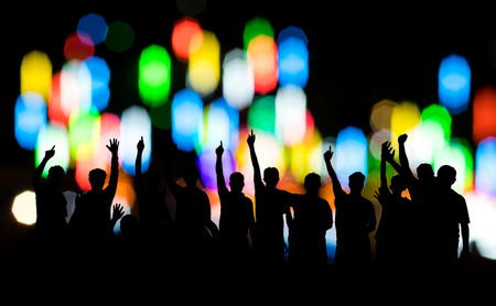 Siluette, a group of men raised their hands with joy in victory, with bokeh, lights, blurred colors as a backdrop.の写真素材