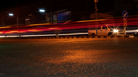 Low view, red light from car taillights, passing through the paved road at night near the village of Thai countryside.の写真素材