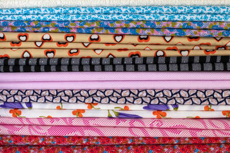 Vertical background, Thai pattern fabric, many different colors, beautiful, folded and hung in a sewing shop.の写真素材