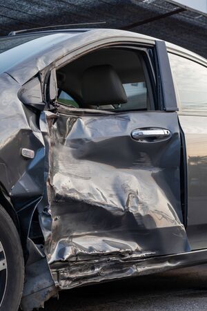 Side view One gray car, which has a broken door from an accident, severely collided with another car...